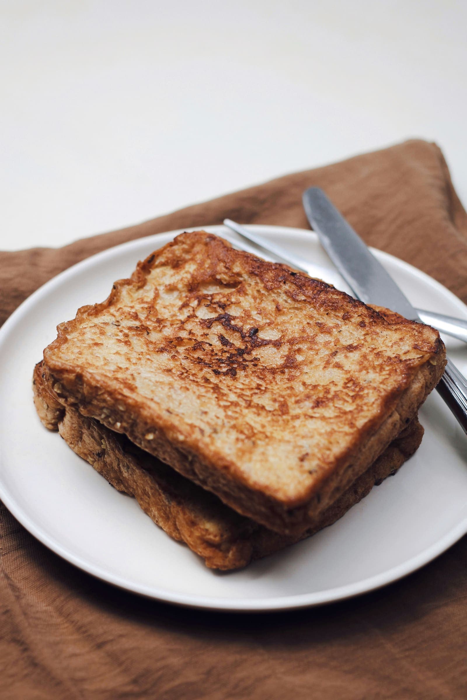 Tranches de pain perdu salé dorées, garnies de fromage fondant et d'herbes